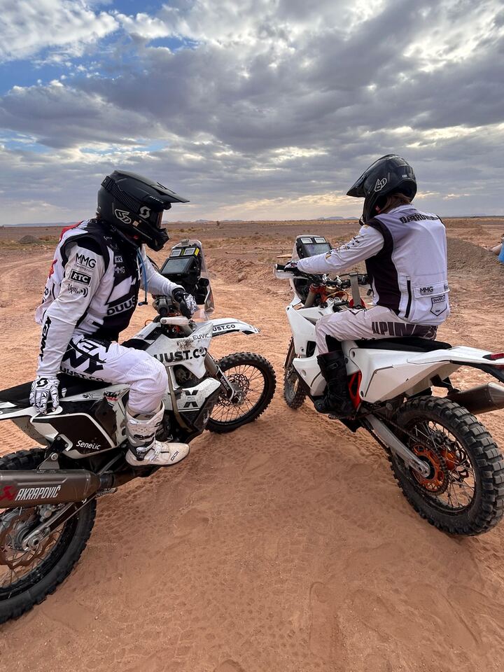 Two riders on rally motorcycles during a stop in the desert