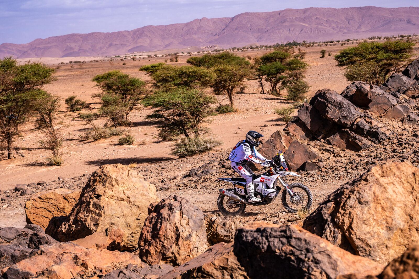 A rally motorcycle passes between large rocks