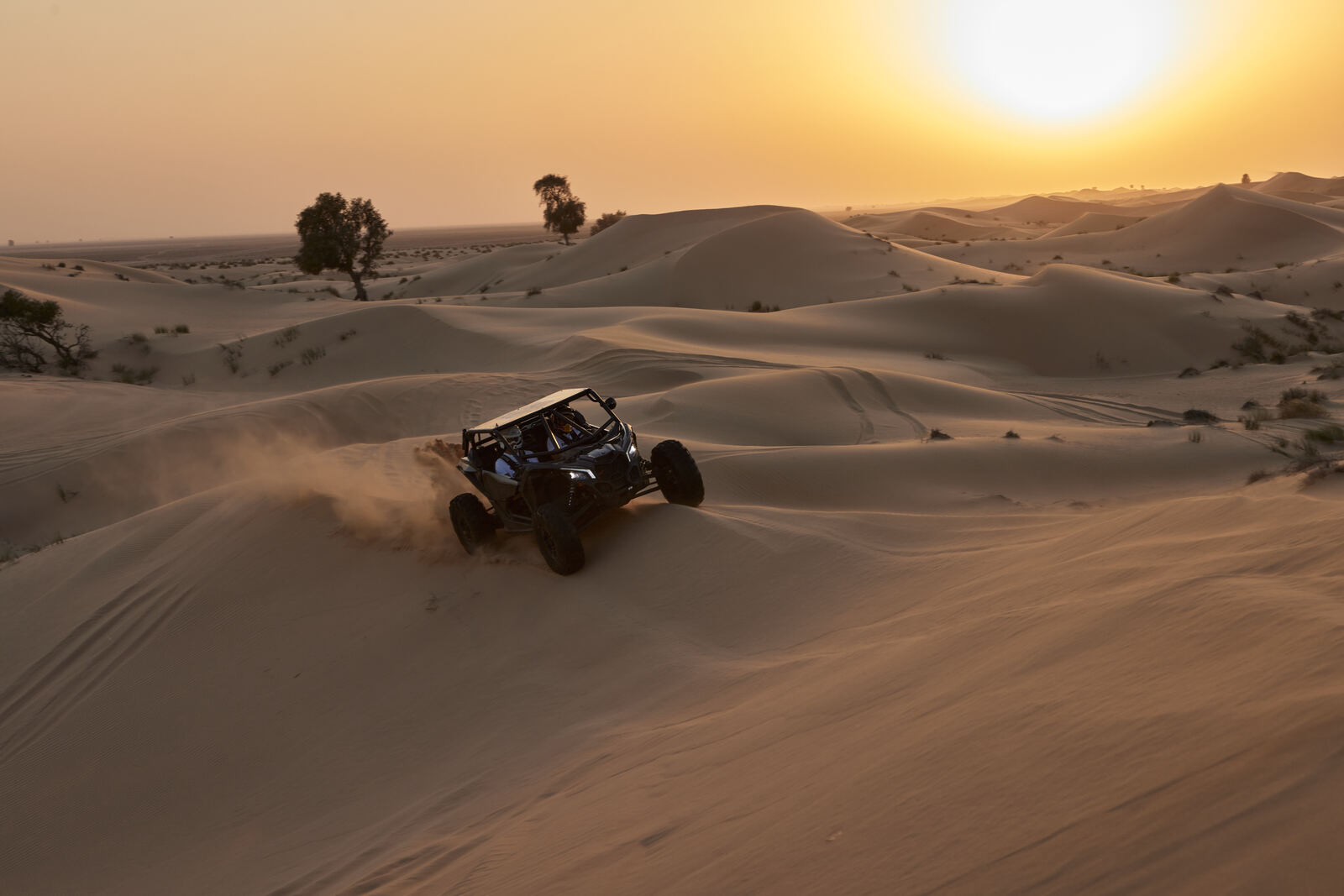 A Can-Am Maverick crossing the Al Qudra dunes at sunset, frame 1 of eight