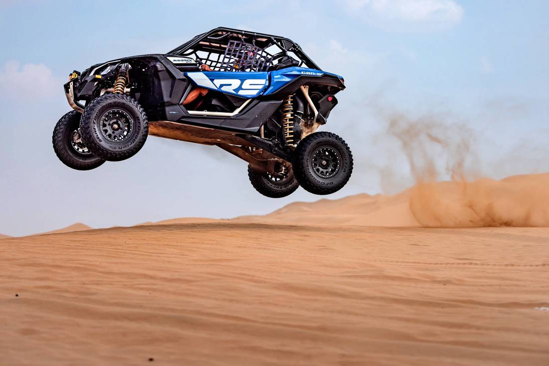 Side-by-side rally car airborne over a dune